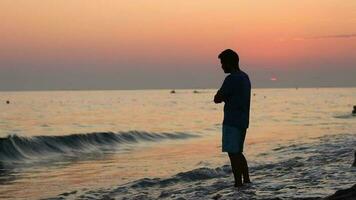 joven hombre en playa puesta de sol video