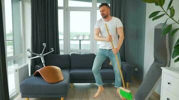 Man cleaning the house and having fun dancing with a broom. Slow motion video