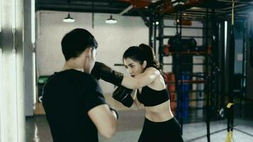 mujer vistiendo rutina de ejercicio ropa con profesional masculino entrenadores boxeo juntos en el gimnasia. video