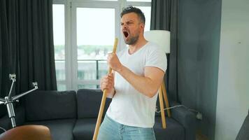 hombre limpieza el casa, teniendo divertido bailando y canto con un escoba. video