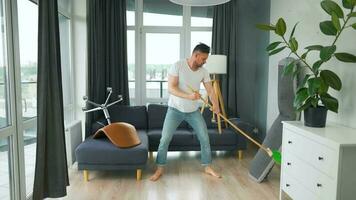 uomo pulizia il Casa e avendo divertimento danza con un' scopa. lento movimento video
