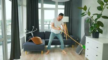 Man cleaning the house and having fun dancing with a broom. Slow motion video