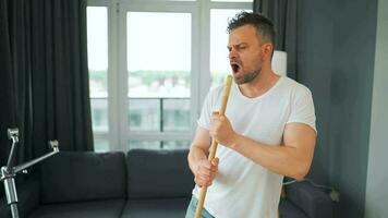 homem limpeza a casa, tendo Diversão dançando e cantando com uma vassoura. video