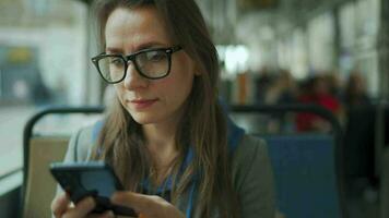 Public transport. Woman in glasses in tram using smartphone video