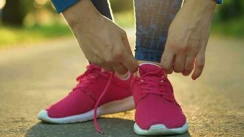 Woman tying shoelaces while jogging or walking at sunset video