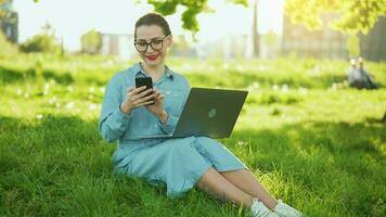 mujer utilizando teléfono inteligente mientras sentado en parque después refinamiento al aire libre trabajo a puesta de sol video