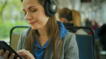 Public transport. Woman with headphone in tram using smartphone video