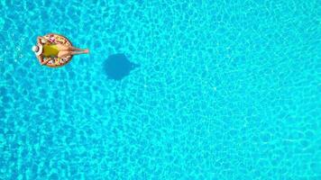 Aerial view of a woman in yellow swimsuit lying on a donut in the pool video