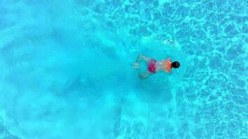 Aerial view of a man in red shorts swimming in the pool, slow motion video