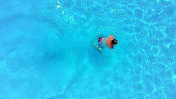 Aerial view of a man in red shorts swimming in the pool, slow motion video