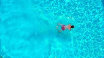 Aerial view of a man in red shorts swimming in the pool, slow motion video