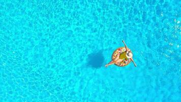 Aerial view of a woman in yellow swimsuit lying on a donut in the pool video