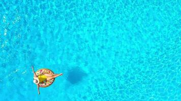Aerial view of a woman in yellow swimsuit lying on a donut in the pool video