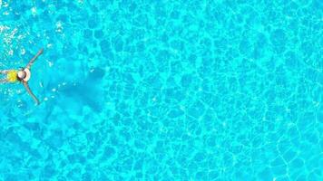aéreo ver de un mujer en amarillo traje de baño nadando en el piscina. verano estilo de vida video