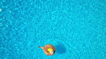 Antenne Aussicht von ein Frau im Gelb Badeanzug Lügen auf ein Krapfen im das Schwimmbad video