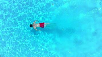 aéreo ver de un hombre en rojo pantalones cortos nadando en el piscina, lento movimiento video