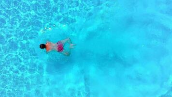 Aerial view of a man in red shorts swimming in the pool, slow motion video