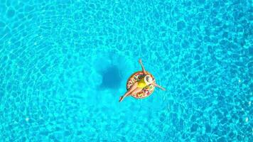 Aerial view of a woman in yellow swimsuit lying on a donut in the pool video