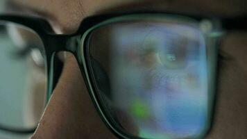 Woman in glasses looking on the monitor and surfing Internet at night. The monitor screen is reflected in the glasses. Work at night video