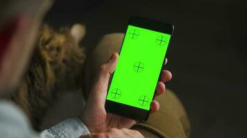 man använder sig av smartphone med grön mock-up skärm i vertikal läge och strök de fluffig katt. man bläddring internet video