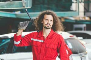retrato de un joven coche mecánico en reparar cochera, técnico hombre trabajando en auto reparar tienda foto