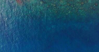 Aerial drone view of clear turquoise sea and waves over the rocky coastline video