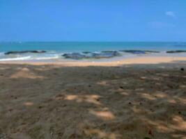 junto a la playa difuminar antecedentes vista, blanco playa con brillante azul cielo antecedentes foto