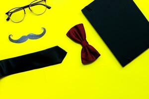 Flat lay fathers day on yellow background. Mockup diary. Tie, glasses, mustache photo