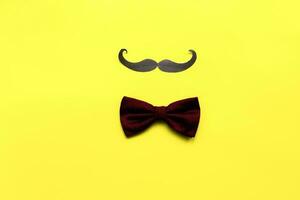 Flat lay mustache and bow tie on yellow background. Happy fathers day. Fathers day card photo