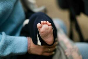 el bebé es en el brazos de el madre. el recién nacido duerme en el calle. bebé pie foto