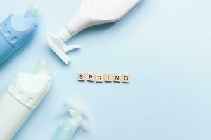 Flat lay spring from wooden letters on a blue background. Cleaners. Cleaning. Cleaning bottle mockup photo