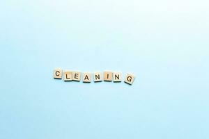 The word cleaning made of wooden letters. Flat lay cleaning from letters on blue background photo