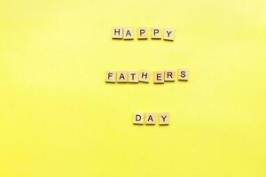 Happy fathers day. Father's day in wood lettering. Flat lay happy fathers day on yellow background photo