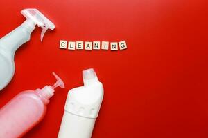 Flat lay cleaning products and sponges on a red background. Letter word cleaning photo