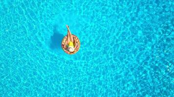 Aerial view of a woman in yellow swimsuit lying on a donut in the pool video