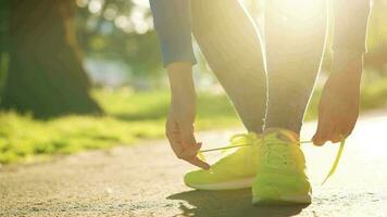 Woman tying shoelaces while jogging or walking at sunset video