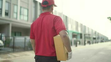 Back view.Delivery man holding parcel boxes finding Customer home Village. video