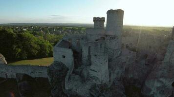 Aerial view on Castle in Ogrodzieniec at sunset. Stone medieval castle built on a rock, made of white stone. Filmed on FPV drone video
