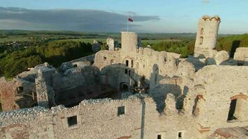 Aerial view on Castle in Ogrodzieniec at sunset. Stone medieval castle built on a rock, made of white stone. Filmed on FPV drone video