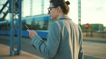 Woman in a coat, walking around the city in the early morning and using smartphone, slow motion video