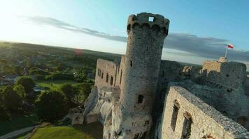 Aerial view on Castle in Ogrodzieniec at sunset. Stone medieval castle built on a rock, made of white stone. Filmed on FPV drone video