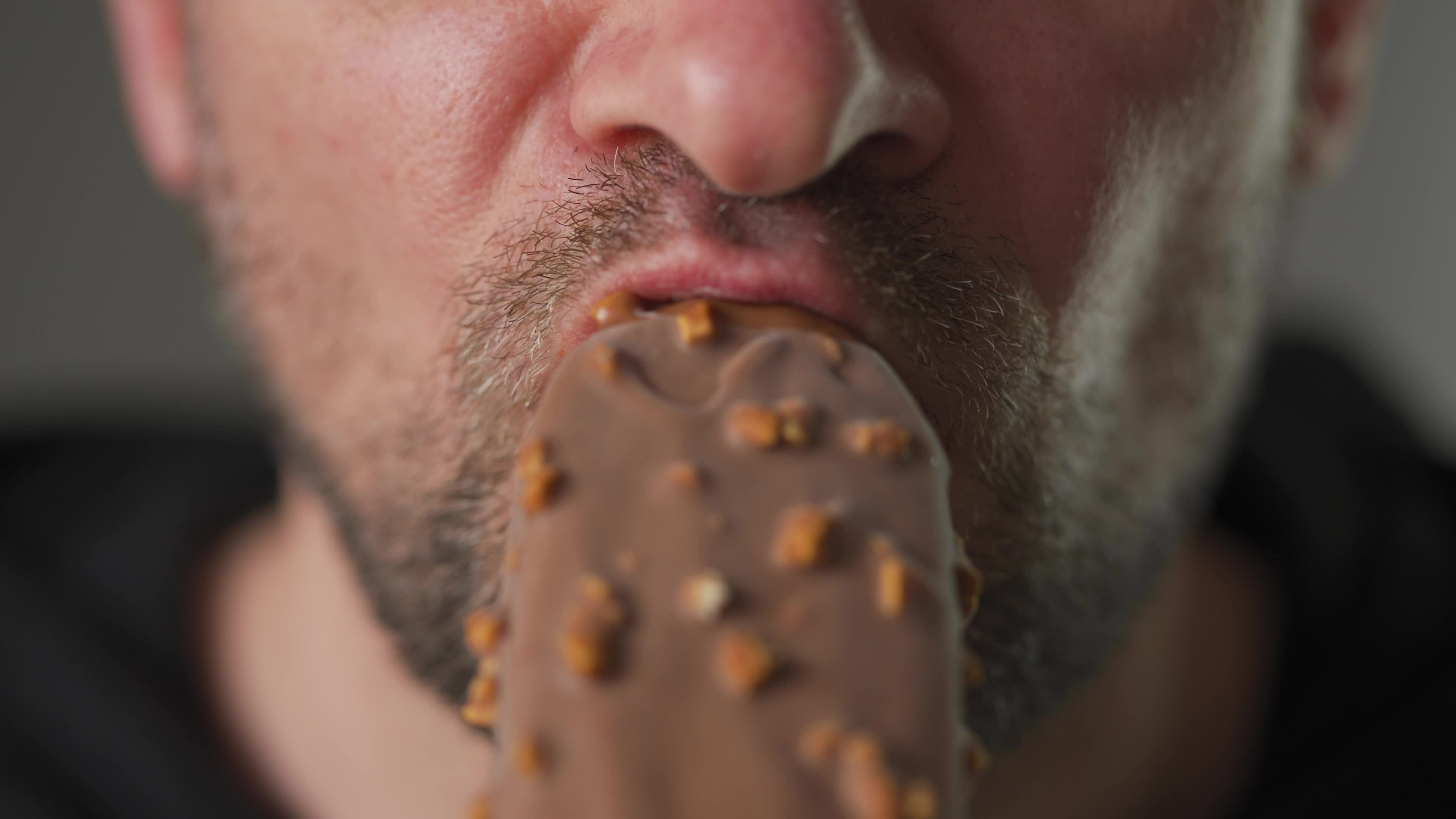 Man Enjoying Eating Chocolate Covered Ice Cream With Nuts 24843193 man-enjoying-eating-chocolate-covered-ice-cream-with-nuts-24843193
