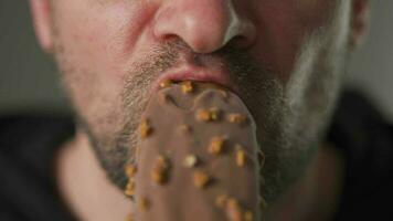 Man enjoying eating chocolate covered ice cream with nuts video