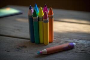 A close-up shot of colourful crayons on a wooden table with paper photo