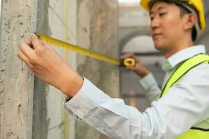 An Asian Engineering man wearing safety helmet checking construction site analyzing about project progress photo