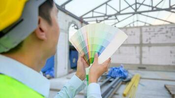 un asiático Ingenieria hombre vistiendo la seguridad casco seleccionando color en construcción sitio foto