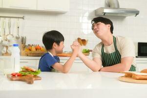Asian boy showing strong arm , playful with his father in home photo