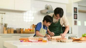 contento joven asiático padre y hijo Cocinando en cocina a hogar foto
