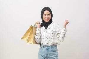 Beautiful musllim woman with hijab holding credit card and shopping bag over white background studio, shopping and finance concept. photo