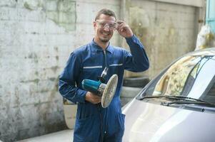 caucásico hombre es utilizando coche pulido máquina en reparar mecánico pintura tienda foto